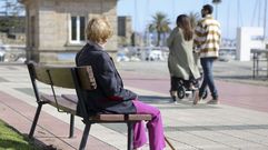 Mujer sentada en un banco en el muelle de Curuxeiras, en foto de archivo.