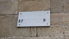 Una placa con el nombre que ha llevado hasta ahora la calle, con la pintura de las letras desaparecida en gran parte