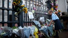 Una ni�a deposita flores en el palacio de Buckingham