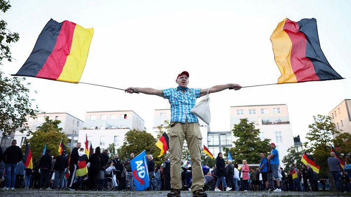 Un hombre enarbola banderas de Alemania en un acto de la campa�a electoral de AfD.