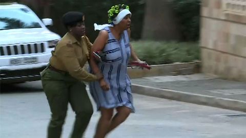Una mujer huye del lugar donde se produjo la explosi�n acompa�ada de un miembro de las fuerzas de seguridad