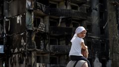 Un hombre camina con una ni�a a hombros ante un edificio destruido en Borodianka, en la regi�n de Kiev
