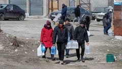 Un grupo de civiles carga botellas de agua en Mari�pol