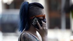 Una mujer con mascarilla habla por tel�fono