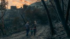 Un hombre mayor pasea con dos ni&ntilde;os por terreno quemado en el incendio que el verano pasado quem&oacute; 1.800 hect&aacute;reas en Pant&oacute;n y Sober
