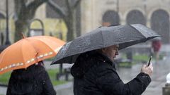 Un hombre bajo la intensa lluvia en Gijn, Asturias