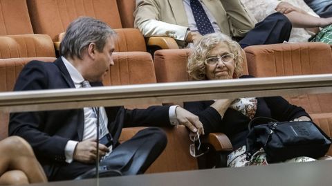 Manuela Carmena charla como Antonio Miguel Carmona en la tribuna de invitados de la Asamblea de Madrid