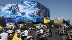 Una carrera militar de motos celebrada este viernes en Teher�n pasa ante un mural alusivo a la guerra
