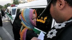 Un polica de la moral iran comprueba la identidad de una mujer detenida durante las protestas en Tehern