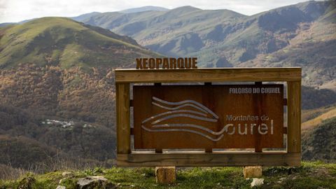 Un letrero con el logo oficial del geoparque frente al bosque de la Devesa da Rogueira, en el municipio de Folgoso do Courel