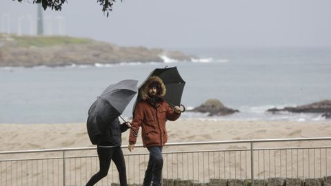 Obligatorio llevar paraguas hoy en la comunidad gallega. En la imagen, gente paseando por el paseo martimo de A Corua