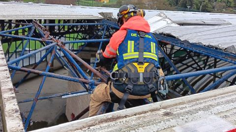 Un bombero inspeccionando la cubierta del estadio de A Malata, levantada por el viento 