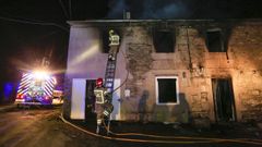 Momento en que los bomberos acceden a la casa incendiada, el pasado s�bado en Vilalba. 