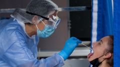 Un sanitario recoge una muestra a un joven para hacer una PCR