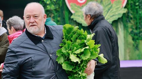 Asistente a la feria con una mada de grelos bajo el brazo.