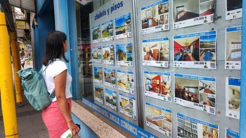 Una joven mirando el escaparate de una inmobiliaria en A Coruña