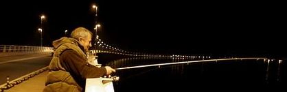 Un hombre aprovecha la iluminaci�n nocturna del puente de A Illa de Arousa para practicar la pesca deportiva.