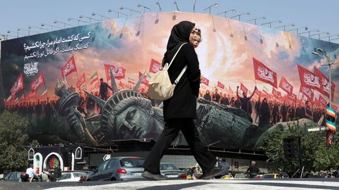 Una mujer pasea frente a un mural con propaganda proiran� y antiamericana.