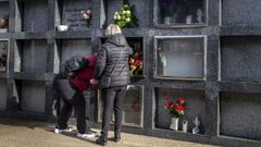 Dos personas en una l�pida justo al lado de uno de los nichos profanados y que ya ha sido tapiado