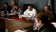 El portavoz del BNG, en primer plano, con miembros del PP y el secretario, al fondo, en el pleno.