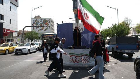 Una mujer sostiene una bandera de Ir�n en una calle de Teher�n