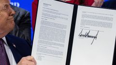Donald Trump sonr�es mientras muestra el documento de constituci�n de la Junta de Paz, en Davos