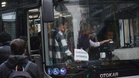 Usuarios accediendo a un autobs marcado con el cartel de servicios mnimos.