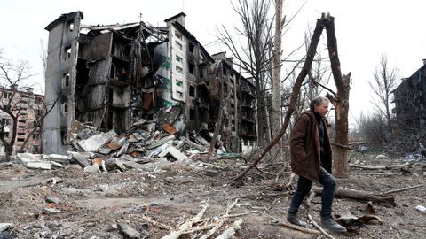 Un hombre camina cerca de un edificio residencial destruido 