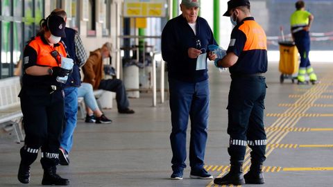 Miembros de protecci�n civil reparten mascarillas este lunes en la estaci�n de autobuses de Oviedo