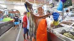 Santi, de Pescados Cachadas, sostiene un pulpo frente a su puesto en la plaza de Pontevedra