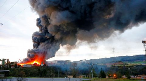 Los Bomberos de Gijón trabajan en las labores de extinción de un incendio producido esta tarde en una nave industrial ubicada en San Andrés de los Tacones (Gijón). El siniestro, en el que no se han producido daños personales, se originó por causas desconocidas en la empresa de desguaces Grupo Riestra