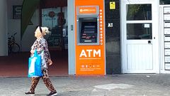 Una mujer camina frente a un cajero autom�tico en Portugal.