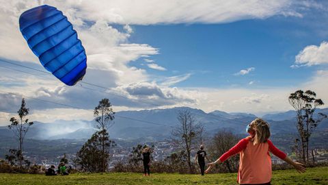 Un grupo de personas vuelan una cometa aprovechando el fuerte viento en la cumbre del monte Naranco