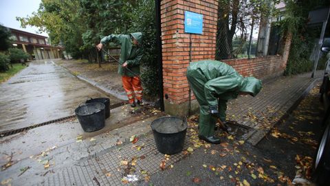 Operarios municipales limpiando el alcantarillado esta maana en la entrada del colegio