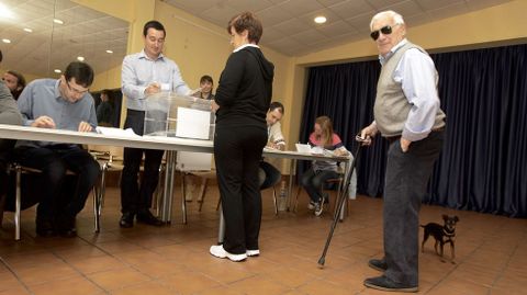 Un hombre espera para votar, acompaado por su perro
