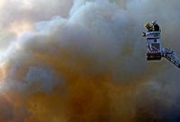 Dos bomberos ante la espesa columna de humo generada por el incendio de una nave.