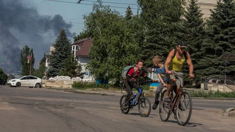Un hombre y dos ni�os huyen en bicicleta de los bombardeos rusos en la localidad de Lisichansk, en la regi�n de Lugansk