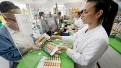La farmac�utica M�riam P�rez entrega un dosificador de pastillas a Carmen Ortigueira, que cuida a dos mujeres