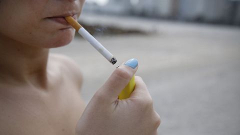 Una mujer enciende un cigarrillo en la playa de Riazor