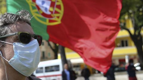 Un hombre celebra el Primero de Mayo en un parque de Lisboa, con la bandera portuguesa ondeando al fondo