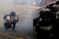 Un manifestante se arrodilla ante una barricada montada por la polic�a.