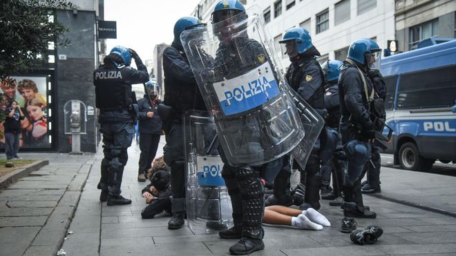 Agentes de la polic&iacute;a italiana, equipados con material antidisturbios, rodean a una persona que yace en el pavimento durante unos disturbios cerca de la Piazza del Duomo, en Mil&aacute;n (Italia) a mediados de octubre. .