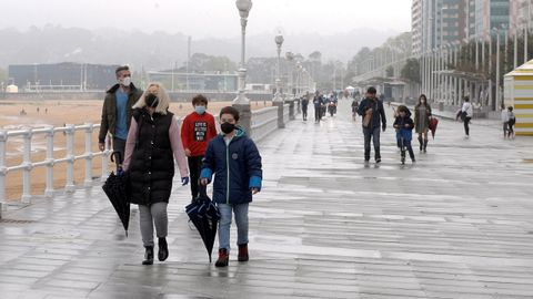 Ni�os con sus padres paseando por el paseo mar�timo, en Gij�n