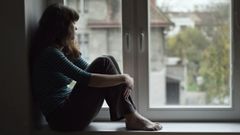 Una joven observa sola por la ventana