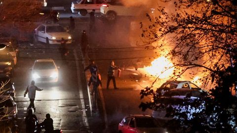 Miembros del�Basij, la fuerza paramilitar formada por voluntarios, sofocan un fuego en una calle de Teher�n.