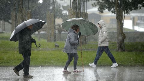 Varias personas caminan bajo la lluvia en Monforte. 