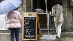 Dos personas delante de un restaurante de Santiago que ofrece comida para llevar.