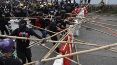Los manifestantes se defienden en kwun Tong con palos y montan barricadas para evitar a los agentes antidisturbios