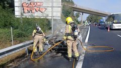 Los bomberos del parque de O Morrazo sofocan el incendio de un coche en la autopista, a la altura de Vilaboa