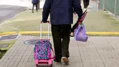 Un abuelo llevando las mochilas de sus nietos.